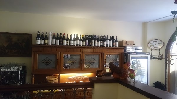 Credenza in legno con le bottiglie di vino piemontese in fila e una gallina in ceramica sul bancone