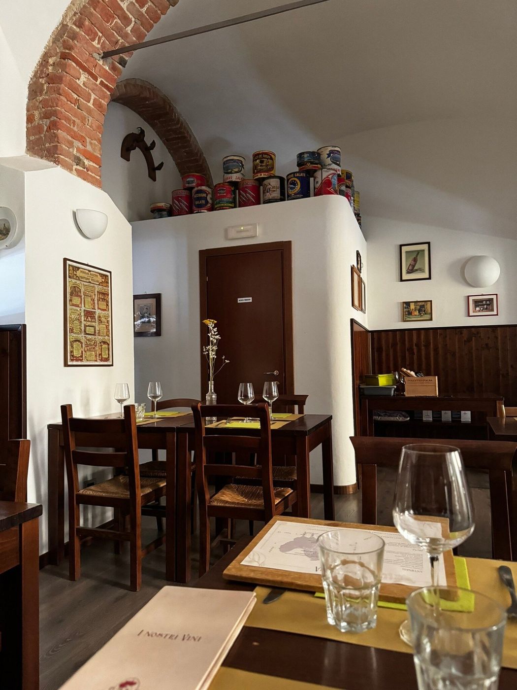 Angolo della sala con arco in mattoni, barattoli di latta d’epoca e tavoli in legno